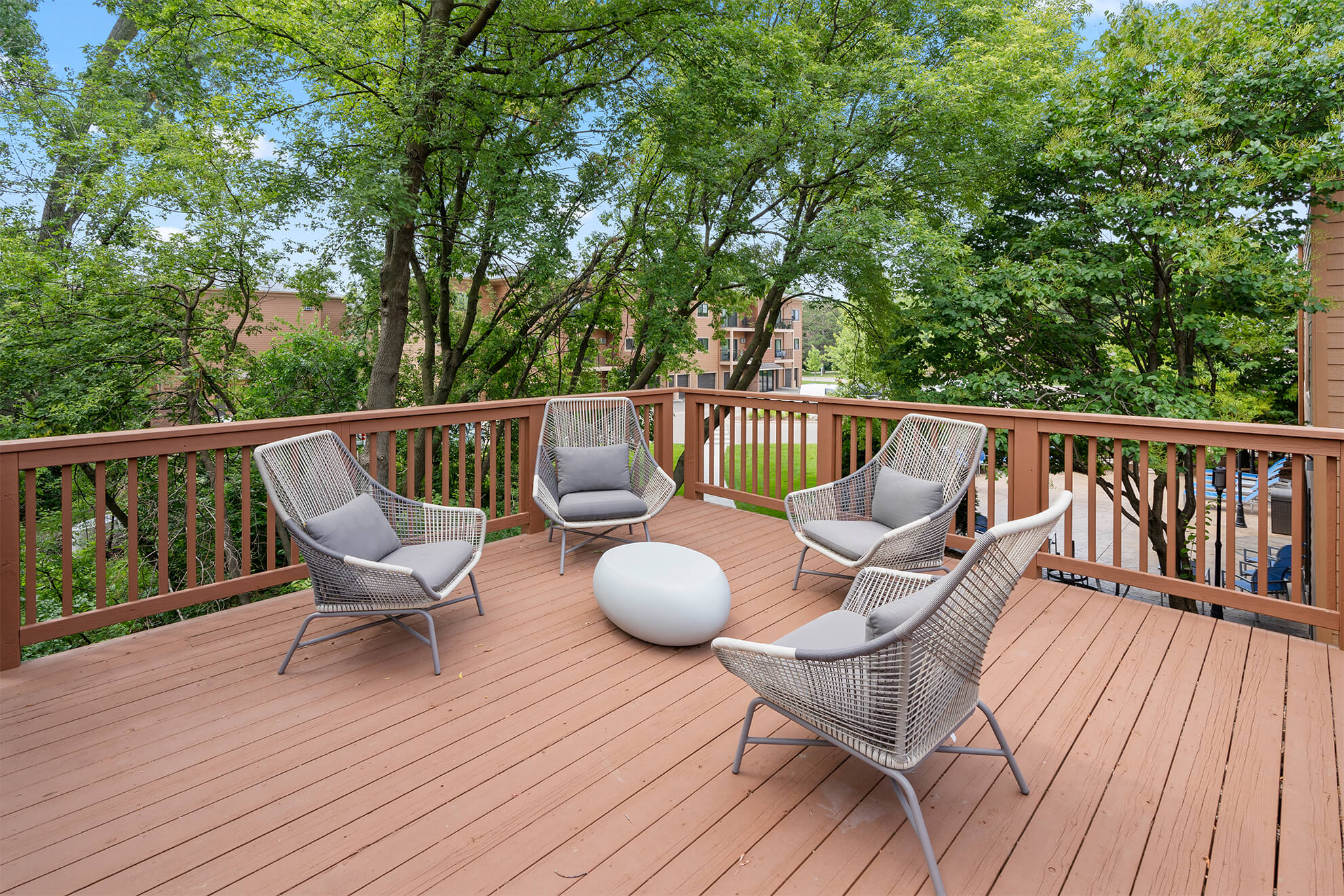 Outdoor deck with modern patio chairs and a central table surrounded by trees