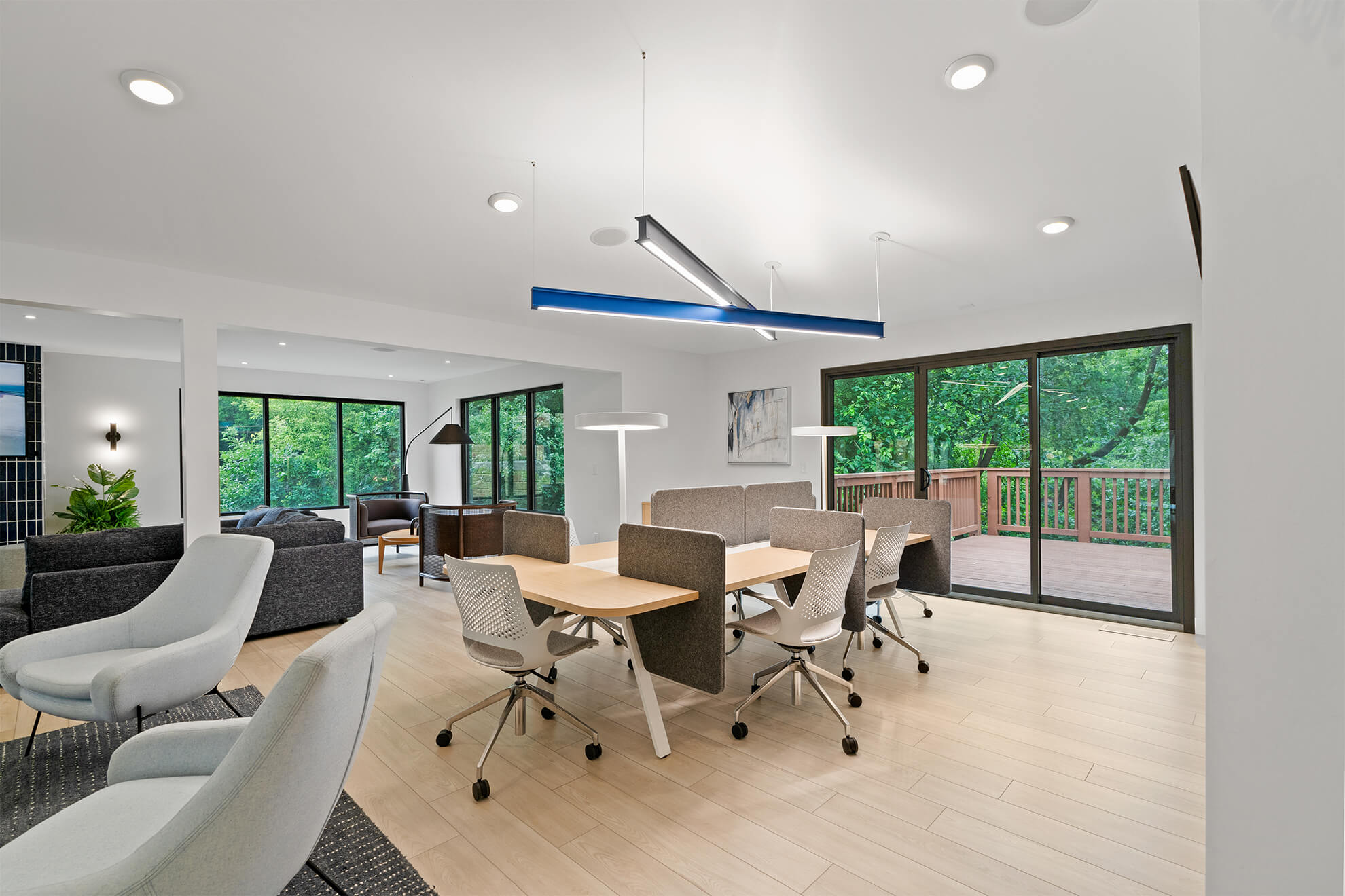 Modern workspace with desk pods and access to an outdoor deck through sliding glass doors
