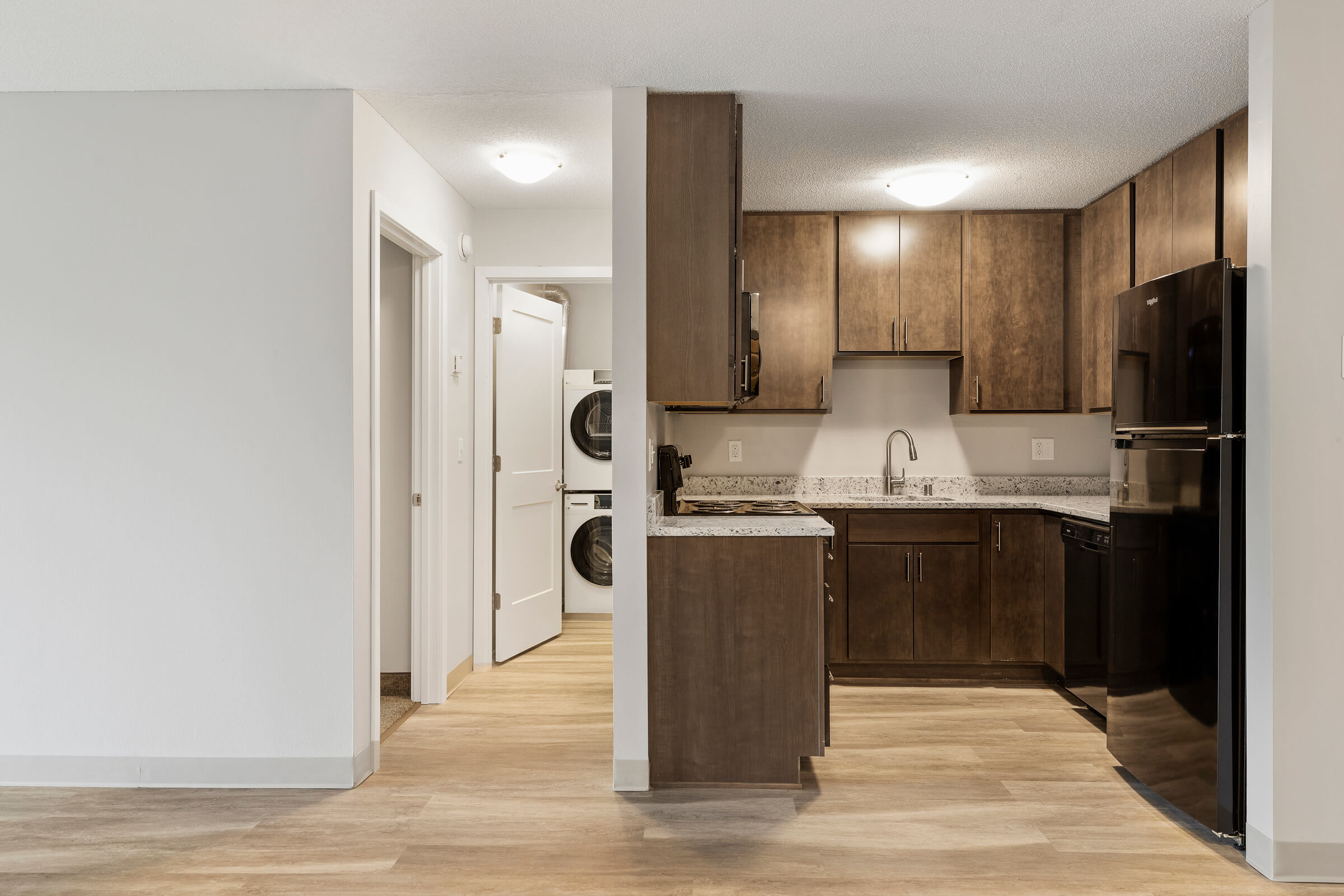Kitchen with brown cabinets and view of stacked washer and dryer