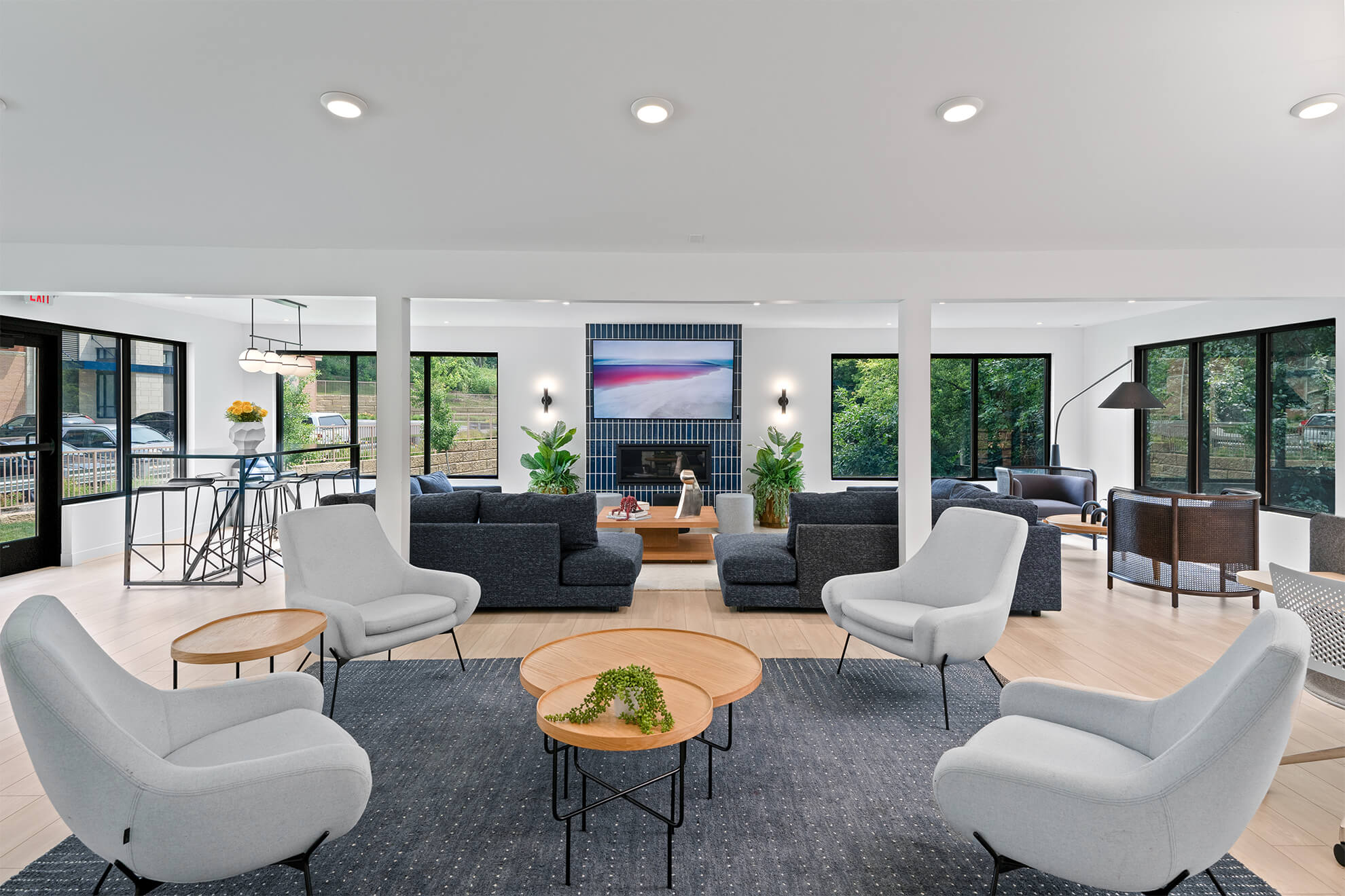 ounge area with modern seating, large windows, and a wall-mounted TV above a fireplace
