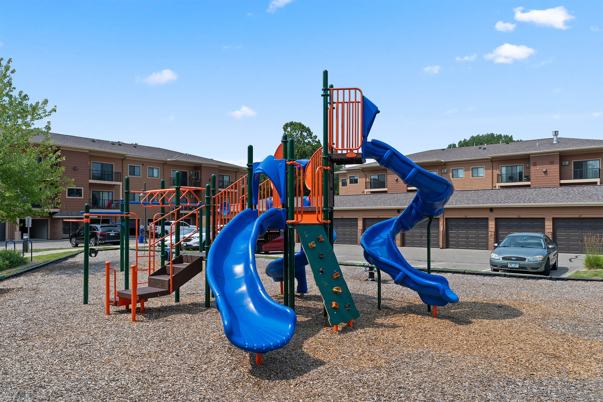 Colorful apartment playground featuring climbing structures and multiple blue slides