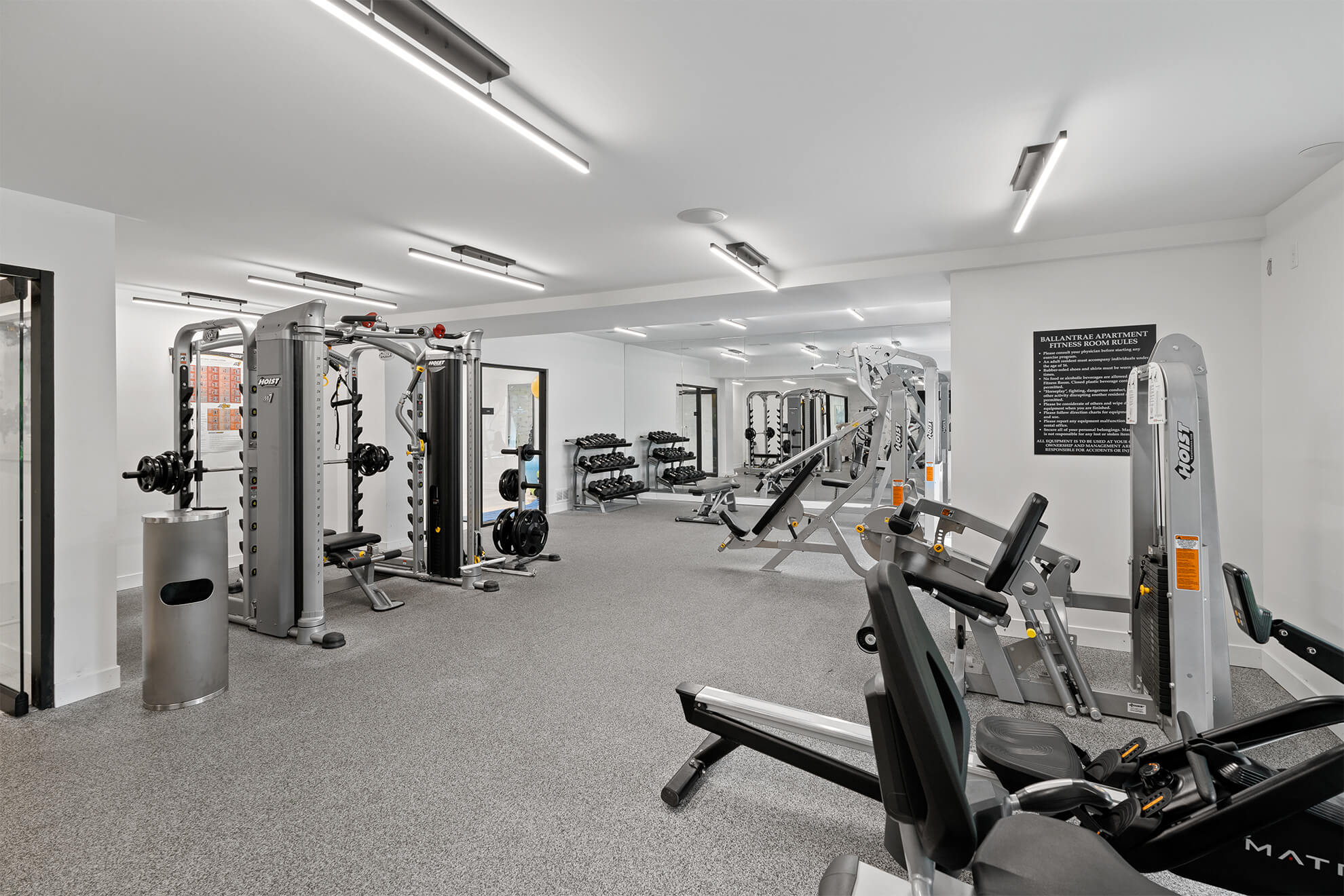 Spacious weight room with strength equipment, free weights, and large mirrors