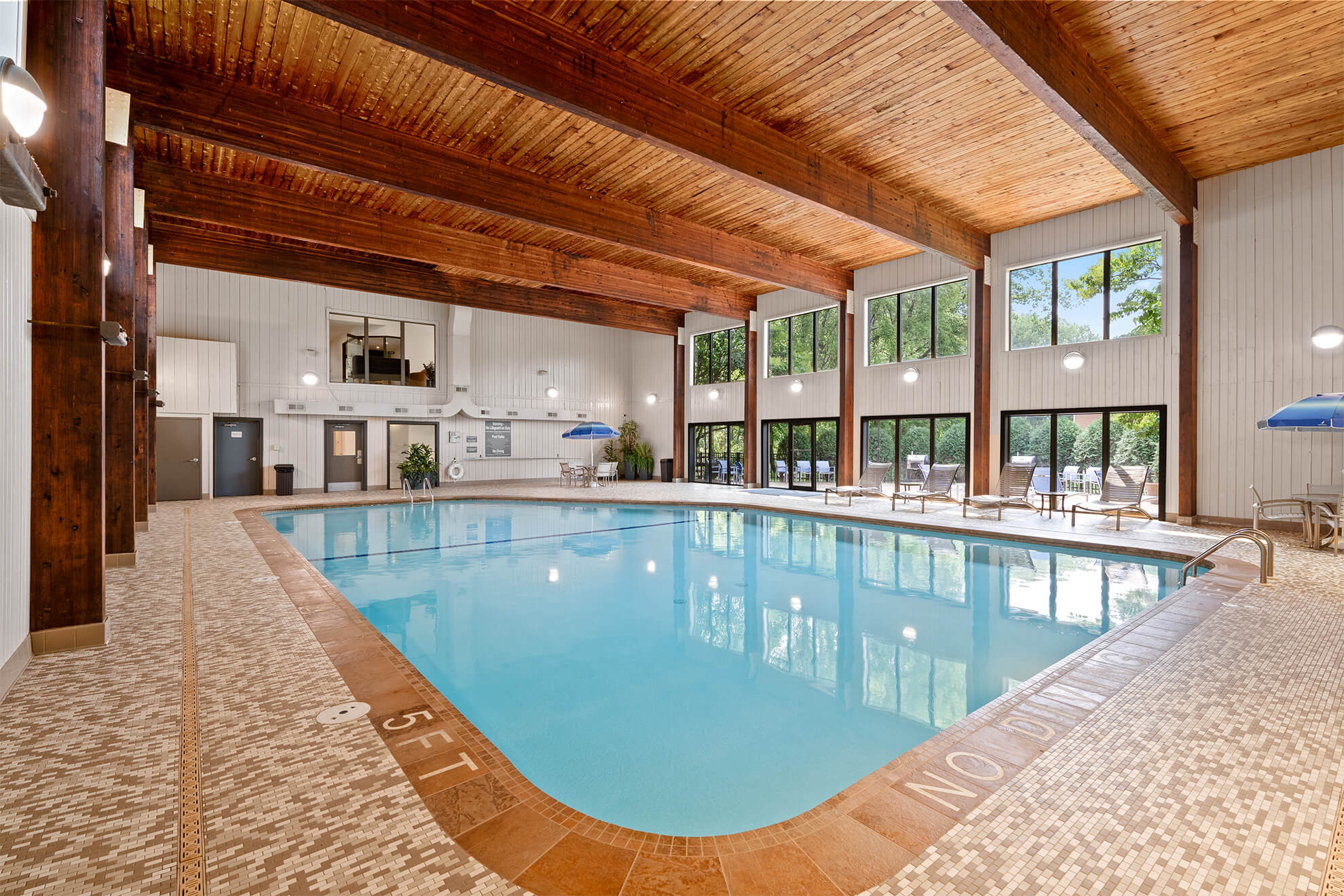 Indoor pool area with lounge chairs and large windows