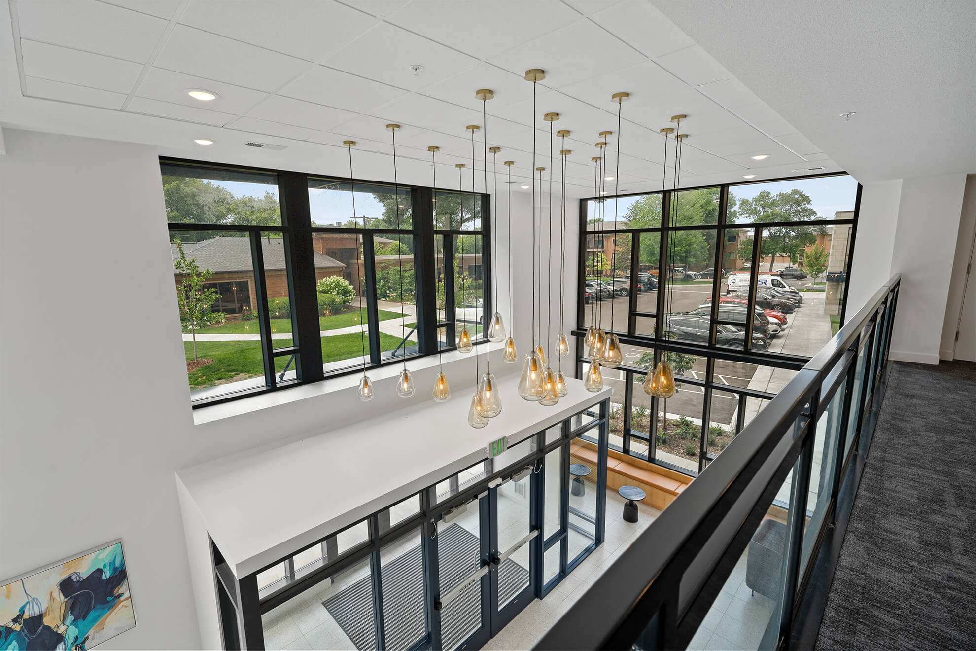 Modern apartment lobby with large windows and hanging pendant lights at Ballantrae Apartments in Minnesota
