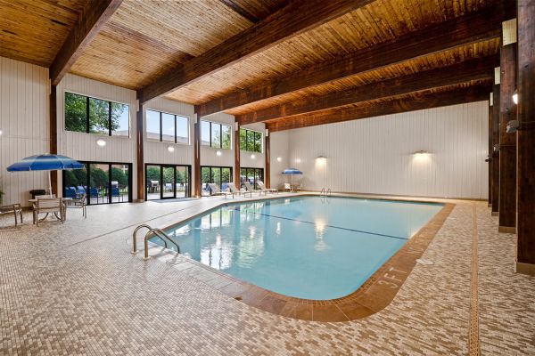 Indoor pool with wood beam ceiling and poolside seating