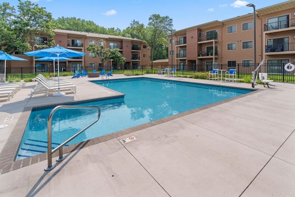 Row of poolside lounge chairs with umbrellas and blue sky