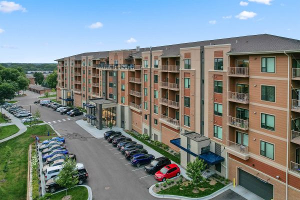Angled view of Ballantrae Apartments showing main entrance, balconies, and parking lot