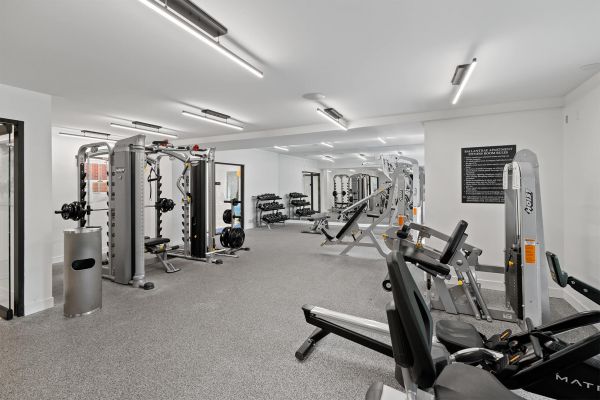 Spacious weight room with strength equipment, free weights, and large mirrors